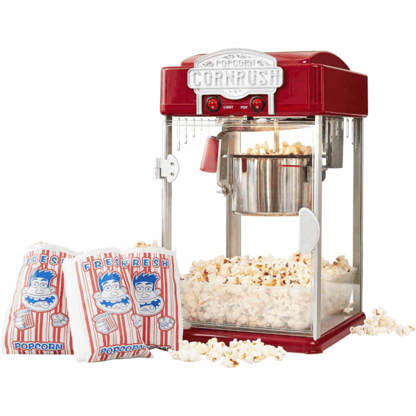 A retro-style red popcorn machine is making popcorn, with two striped popcorn bags and popped popcorn scattered in front of it.
